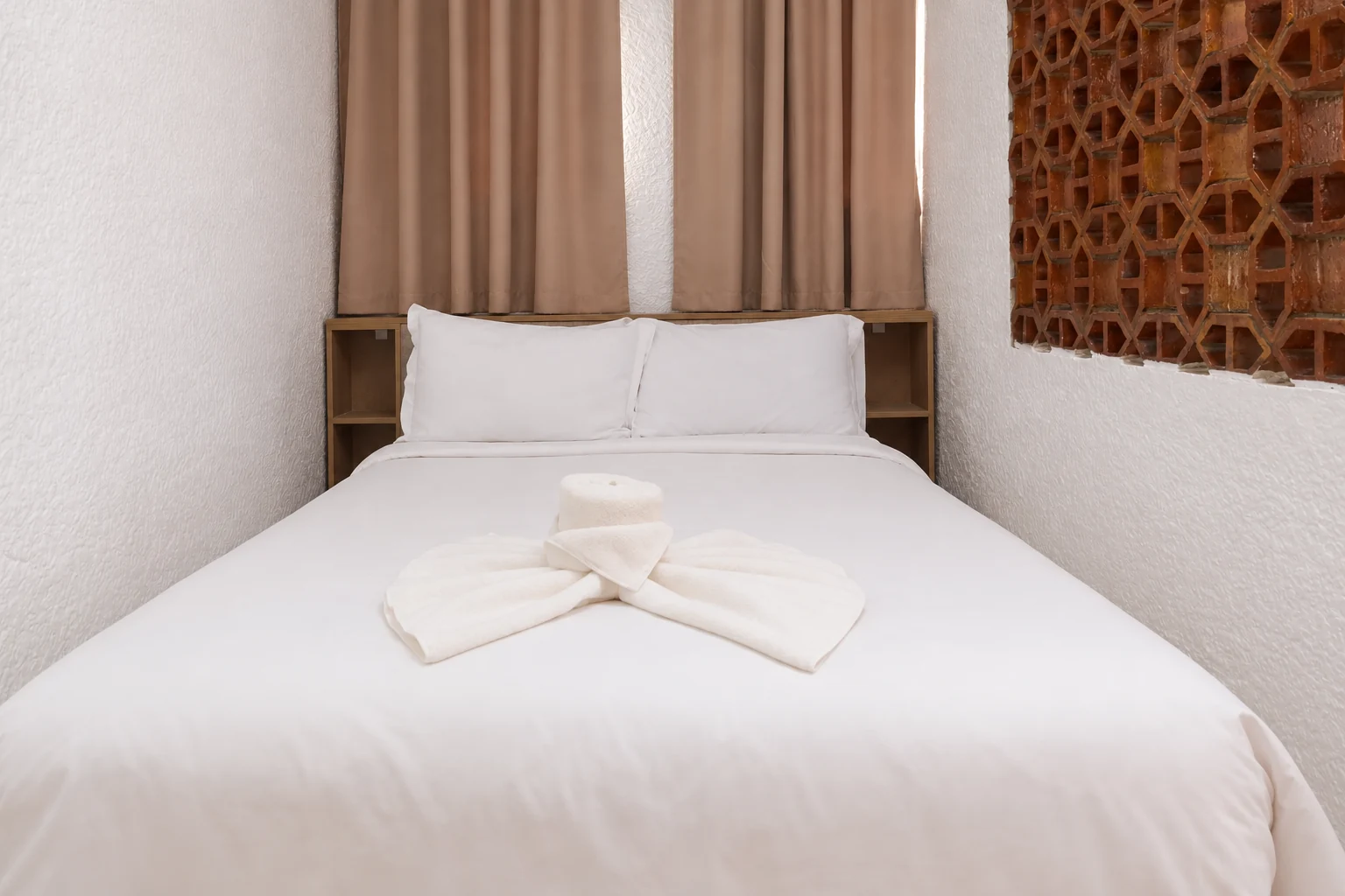Lit double avec linge blanc et rideaux dans une chambre du Studiotel Afoud